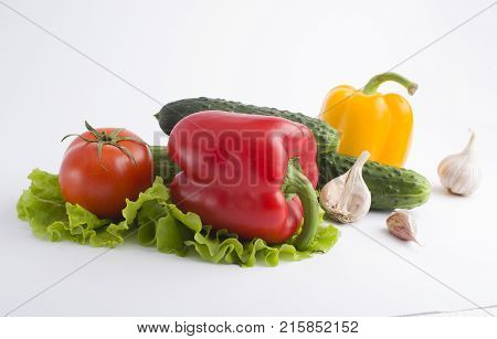 Red peppers and yellow peppers with tomatoes on a white background. Fresh vegetables on a white background. Composition from vegetables. Red and yellow peppers on white background with garlic. Tomato with peppers and cucumber on a white background.