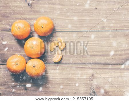 Orange mandarins on the wood table in snow