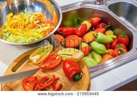 Autumn procuring of crop of ripe multicolored peppers. Whole, halved and sliced into lengthwise slices peppers.