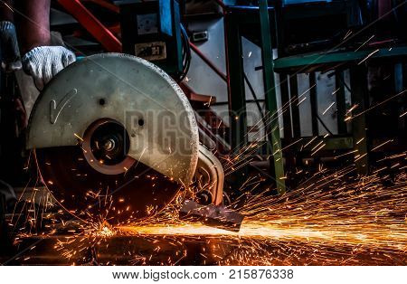 Hand of worker man using machine electricity tool cutting steel and sparks while cutting iron.background