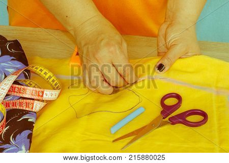 needlework and hand quilting in the workshop of a tailor woman - on the desktop of thread scissors. female in costume sewing
