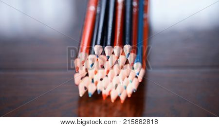 Multicolored pencils on the table. A stack of colored pencils tied together. A scattering of writing supplies and stationery.