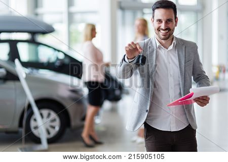 Handsome young salesman at car dealership selling vehichles