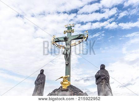 Jesus hanging on the cross in a statue. Inri sculpture against blue partly cloudy sky.