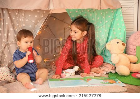 Cute children playing in hovel at home