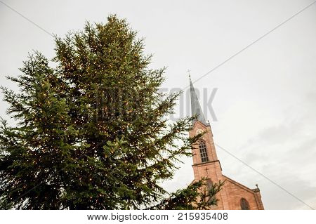 Majestic Christmas tree with yellow illumination and Friedenskirche church in Marktstrasse view from below
