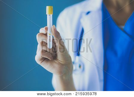 Female medical or research scientist or doctor using looking at a test tube of clear solution in a lab or laboratory