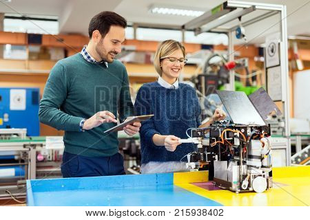 Young attractive students of mechatronics working on project together