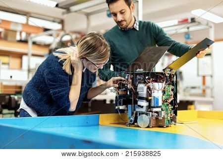 Young attractive students of mechatronics working on project together