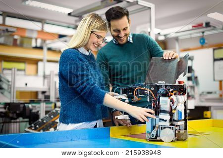 Young attractive students of mechatronics working on project together