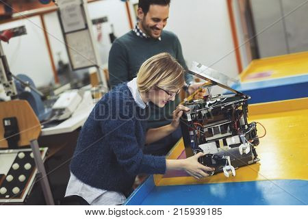 Young attractive students of mechatronics working on project together