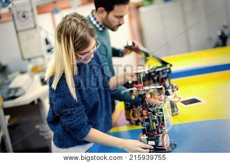 Young attractive students of mechatronics working on project together