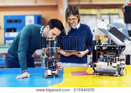 Young attractive students of mechatronics working on project together