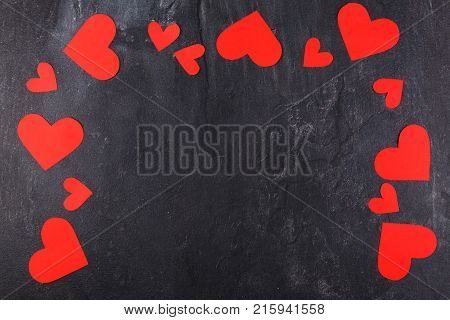 Hearts carved, red of different sizes lie an arch along the perimeter on a stone wall