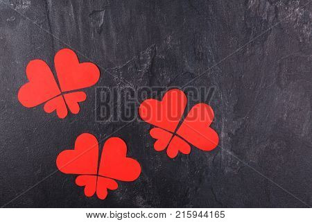 Red hearts carved in different sizes lined up in butterflies close-up on a stone background. View from above