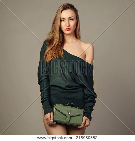 Young woman in hand small green trendy leather bag on gray background