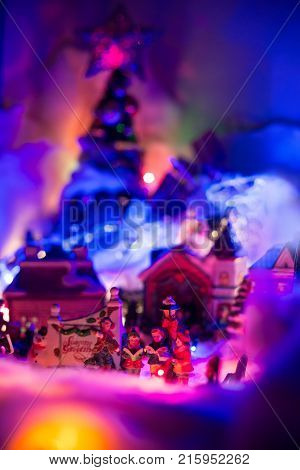 Seasons greeting with kids singing gospel with colorful Christmas village blurred in the background. Holiday festive miniature 
