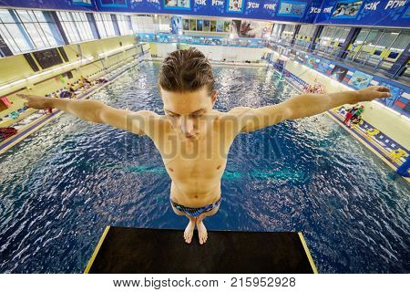 MOSCOW, RUSSIA - SEP 15, 2017: Boy stands ready on diving-tower in Universal sports and entertainment complex Izmailovo. Pool includes swimming pool, children bath and jumping bath.