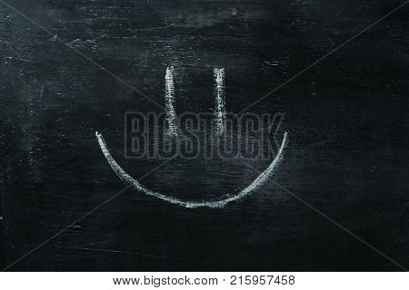 White happy smiley face on a blackboard background, closeup