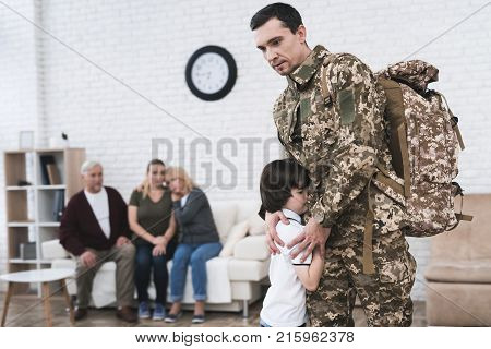 A man goes to military service. He says goodbye to his family and parents. They are sad and embrace.