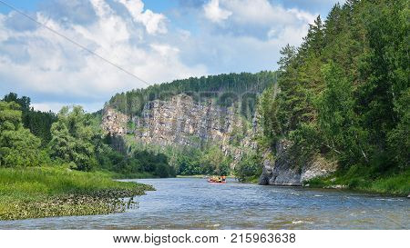 Team of people float down the River on inflatable catamaran among beautiful rocks and mountains of Russia, Bashkortostan, Ay river