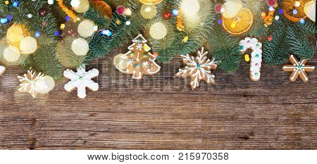 christmas gingerbread iced cookies with fir tree flat lay border, copy space on wooden background banner