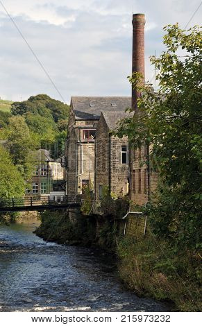 hebden bridge with view of the river calder with stone terraced houses and mill chimney