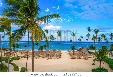 Palm umbrellas on the sandy beach of Bavaro Dominican Republic. View from the hotel side Iberostar Grand Hotel Bavaro