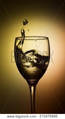 a glass with splashing water on a warm background