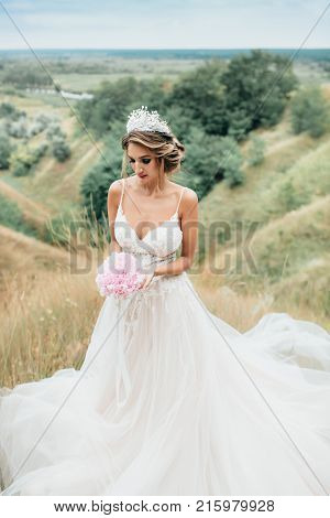 Portrait of a young beautiful bride on a background of a gorgeous view. Girl in wedding dress