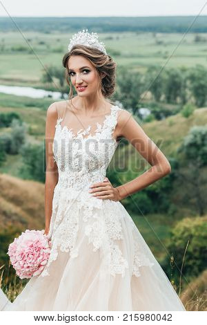 Portrait Of A Young Beautiful Bride On A Background Of A Gorgeous View Of The River And Fields.