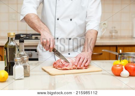 Butcher cutting meat on chopping board, professional cook holding knife and cutting meat