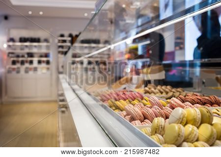 Different types of macaroons on blured background in candy shop