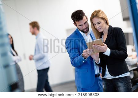 Attractive business couple working on tablet in modern office together