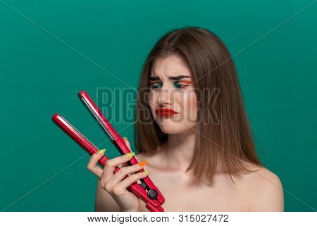Portrait Of Sceptic Beautiful Young Woman With Bright Color Make-up Doing Hair Style Herself With A 