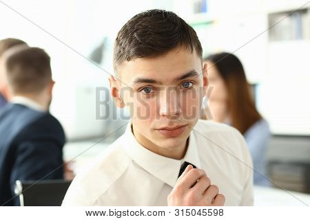 Portrait Of Witty Man Sitting In Big Modern Building And Looking At Camera With Big Concentration An