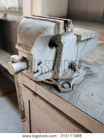 Shallow Depth Of Field Image With A Rusty And Dirty Heavy Iron Vice On A Workbench Inside A Workshop