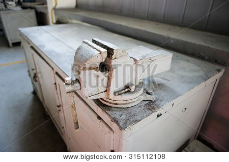 Shallow Depth Of Field Image With A Rusty And Dirty Heavy Iron Vice On A Workbench Inside A Workshop