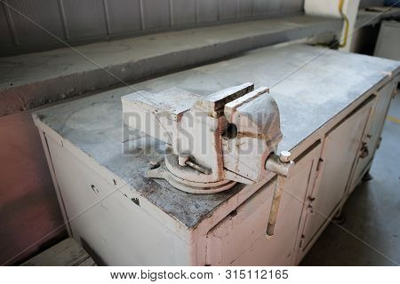 Shallow Depth Of Field Image With A Rusty And Dirty Heavy Iron Vice On A Workbench Inside A Workshop