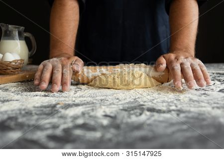 A Man Prepares Dinner At Home, Strong Hands Roll A Roll Of Raw Dough With A Rolling Pin