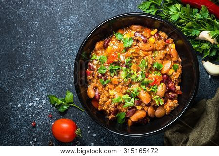 Chili Con Carne From Meat, Beans And Vegetables On Black Stone Table. Traditional Mexican Food. Top 