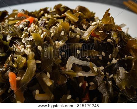 Seaweed Salad With Sesame Seeds Is On A White Plate