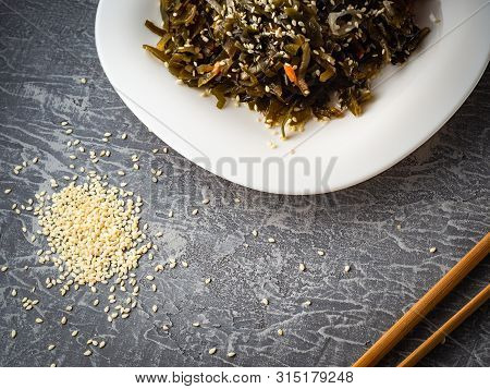 Seaweed Salad With Sesame Seeds Is On A White Plate