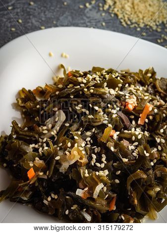 Seaweed Salad With Sesame Seeds Is On A White Plate