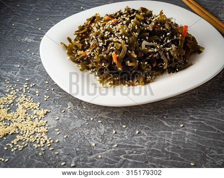 Seaweed Salad With Sesame Seeds Is On A White Plate