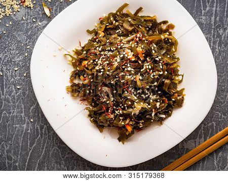 Seaweed Salad With Sesame Seeds Is On A White Plate