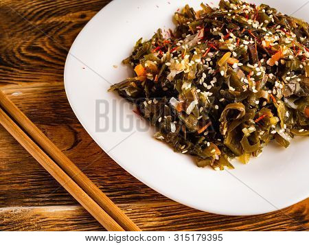 Seaweed Salad With Sesame Seeds Is On A White Plate