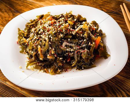 Seaweed Salad With Sesame Seeds Is On A White Plate