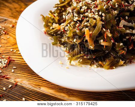 Seaweed Salad With Sesame Seeds Is On A White Plate