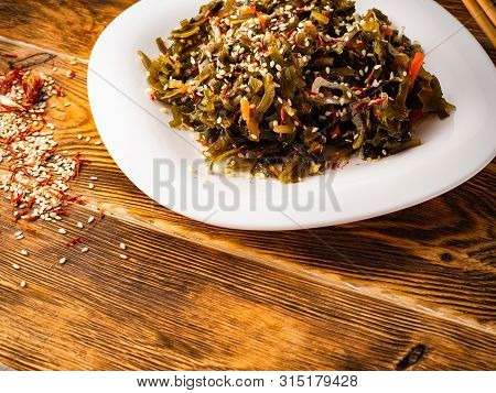 Seaweed Salad With Sesame Seeds Is On A White Plate